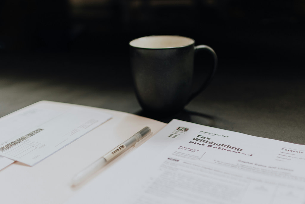 Black mug sitting in front of health insurance tax returns documents