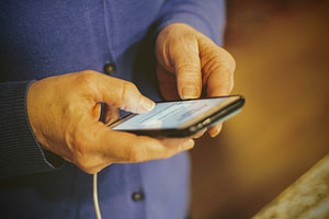 Close up image of a person using a cell phone to report health insurance fraud affecting Nevadans