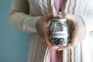 Person holding a savings jar with change in it for Nevada health insurance costs