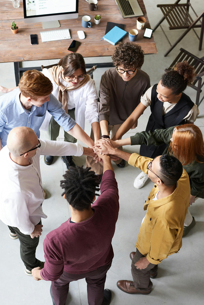 Group of people in an office putting their hands together in a circle because they chose the best employee health insurance in Nevada