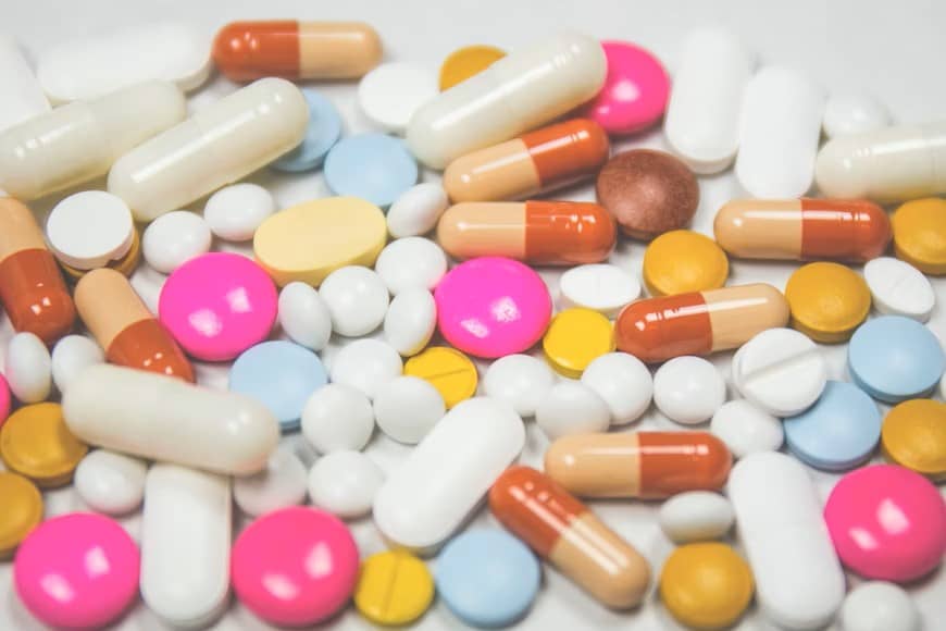 Colorful pills scattered on a white table to signify Reno prescription discounts